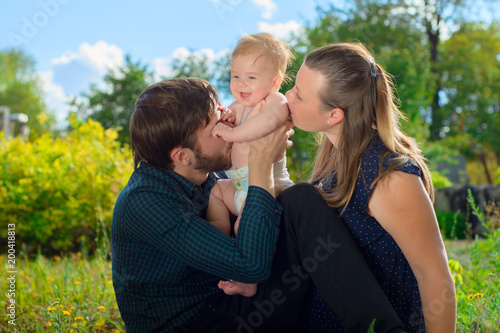 Mom and Dad kiss their son to laugh