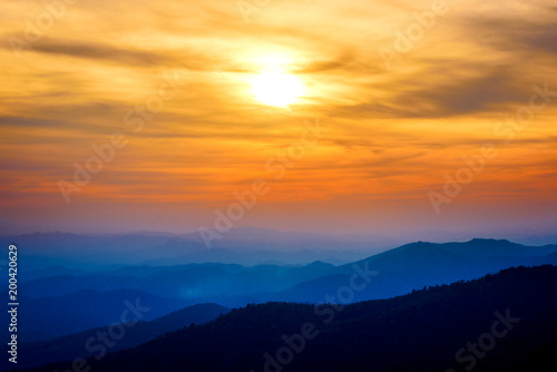 Dramatic sunset and sunrise sky and clouds over blue mountains layers