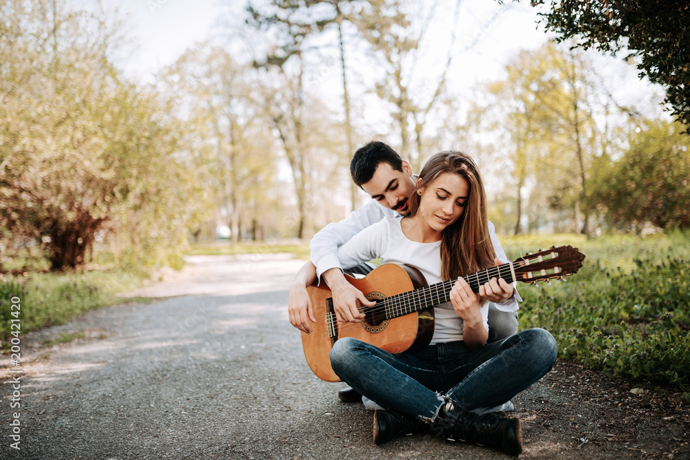Guitar lesson date. Image of couple playing guitar outdoors. Guitar lesson date. Image of couple playing guitar outdoors.