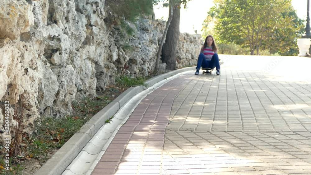 The girl is rolling down the hill on a skateboard. The girl is rolling down the hill on a skateboard.
