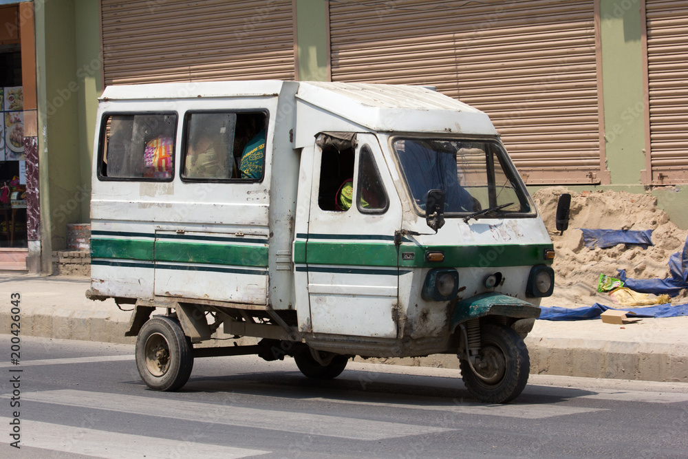 White electric car, minibus with passengers (public transport, fixed route taxi) in Kathmandu, Nepal