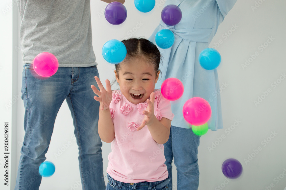 Happy children playing with their parents, having fun with colorful balls.
