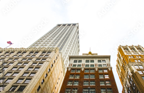 Looking up at ornate art deco buildings with an American flag flying on one