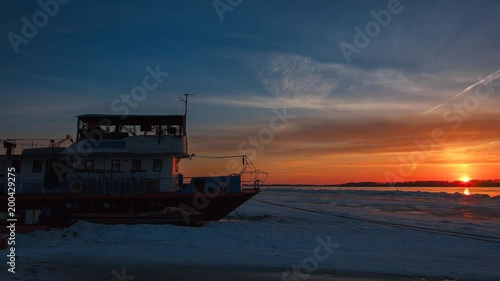 Floating house in the background of a sunset on a frozen river
