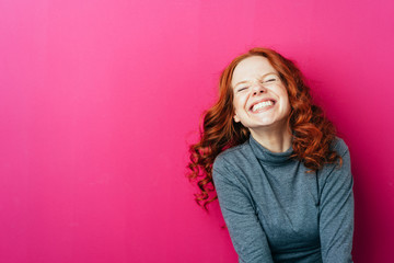 Young laughing woman against pink background