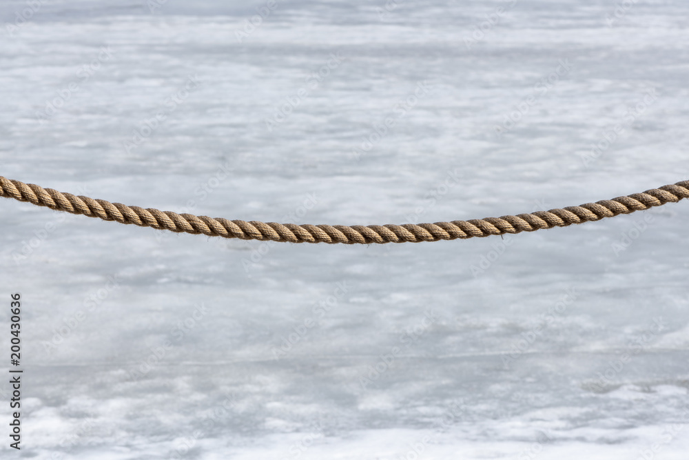 Obraz premium Fence rope on a snow-melting background.