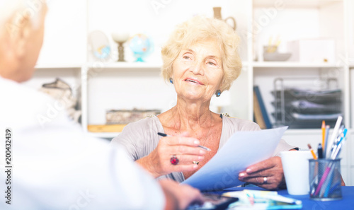 Smiling senior woman discussing with husband bills