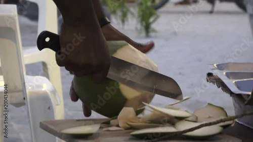 Man cuts off pieces from a young fresh coconut. Maldives video