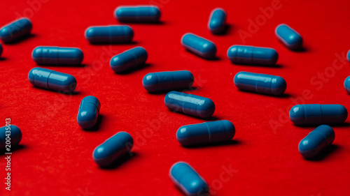 Blue pills capsule on red background Medicine and pharmacy concept.