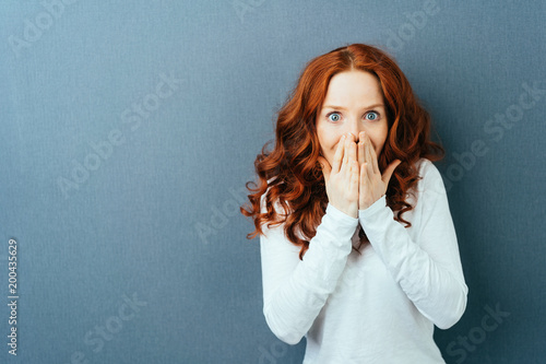 Excited young redhead woman staring at camera photo