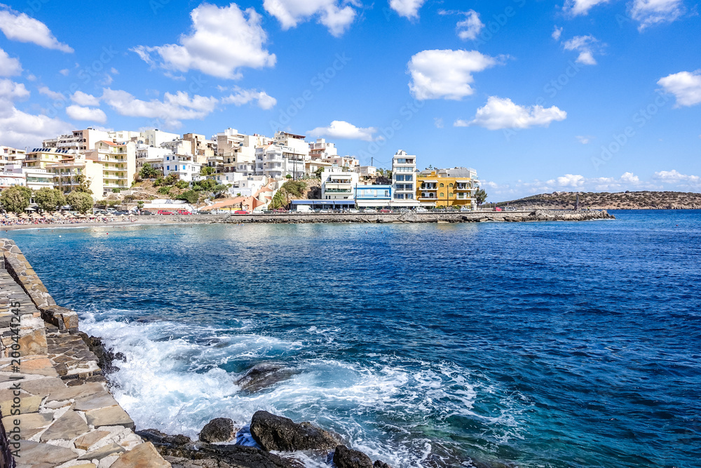 summer sunny day, the shores of the Mediterranean on a small town, beautiful blue skies with white clouds, white waves near the shore