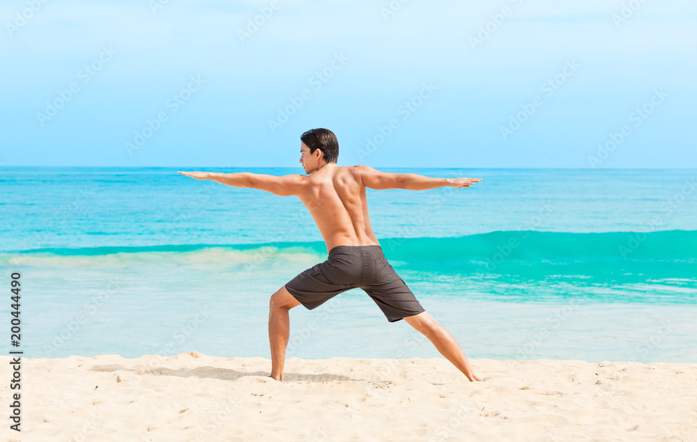 Fit male doing stretching exercise on the beach. 