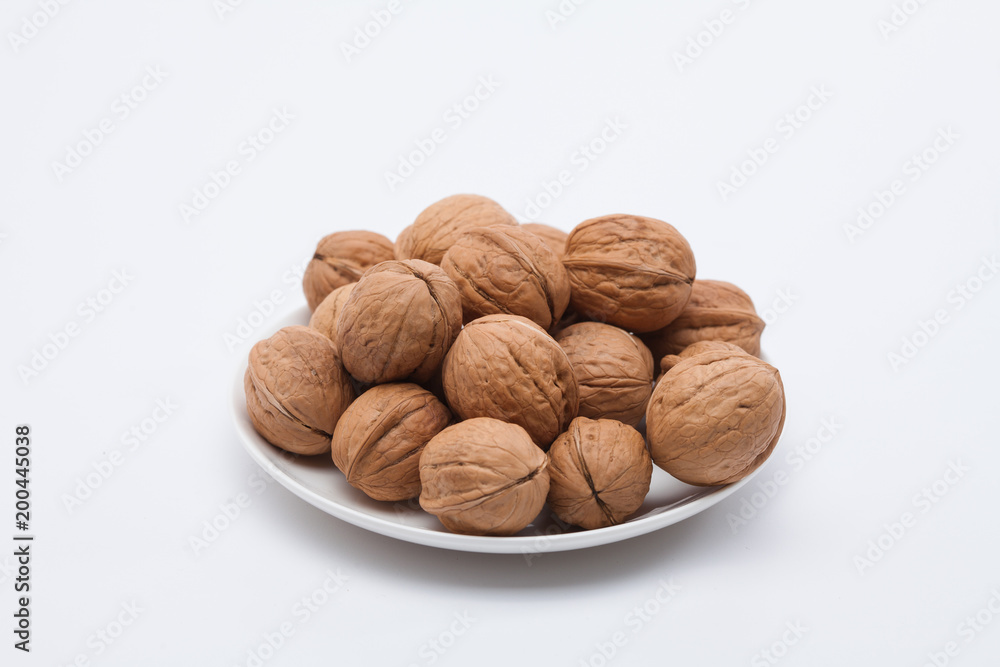 Walnuts on white dish on the white background Walnuts on white dish on the white background