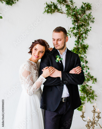 Bride and groom standing on white wall background