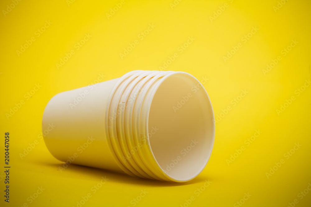 White paper cup on yellow background 