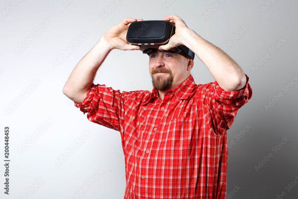 Portrait of bearded man watching virtual reality glasses over gray background with copyspace. Portrait of bearded man watching virtual reality glasses over gray background with copyspace.