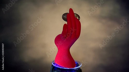   красная кисть руки с  биткоинами зажатыми в пальцах