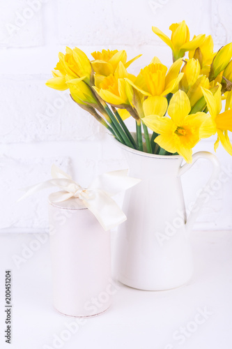 Fototapeta Naklejka Na Ścianę i Meble -  Jar with narcissuses and a gift box at the white background. Spring, mothers day and easter concept