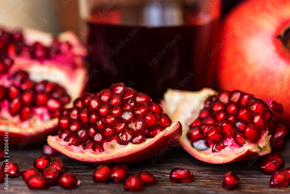 Ripe pomegranates with glass of juice on table Ripe pomegranates with glass of juice on table