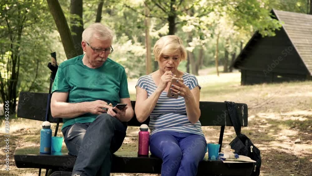 Senior couple sitting with smartphone on bench in the forest
Senior couple sitting with smartphone on bench in the forest