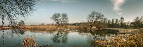 spring evening on the river bank in the city park. panoramic view