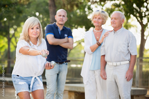 Smiling mature woman and friends playing petanque