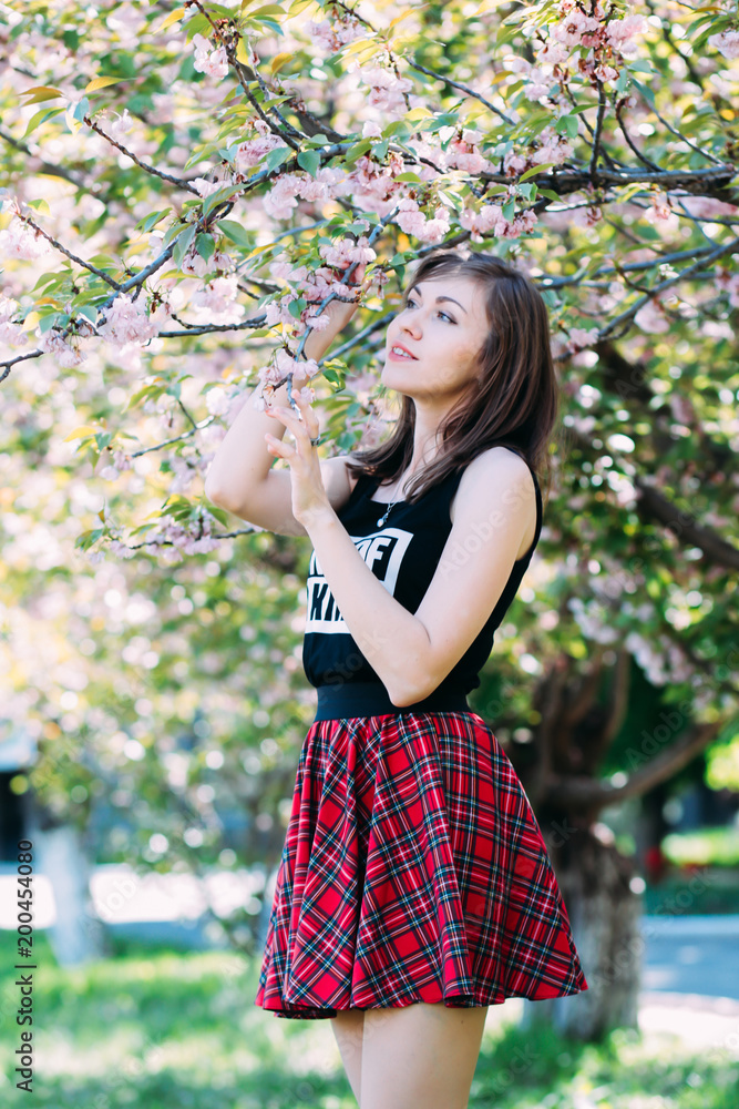 Woman near the blossoming spring tree, enjoying freshness and beauty of nature. Woman near sakura, blooming cherry-tree background. Woman near the blossoming spring tree, enjoying freshness and beauty of nature. Woman near sakura, blooming cherry-tree background.