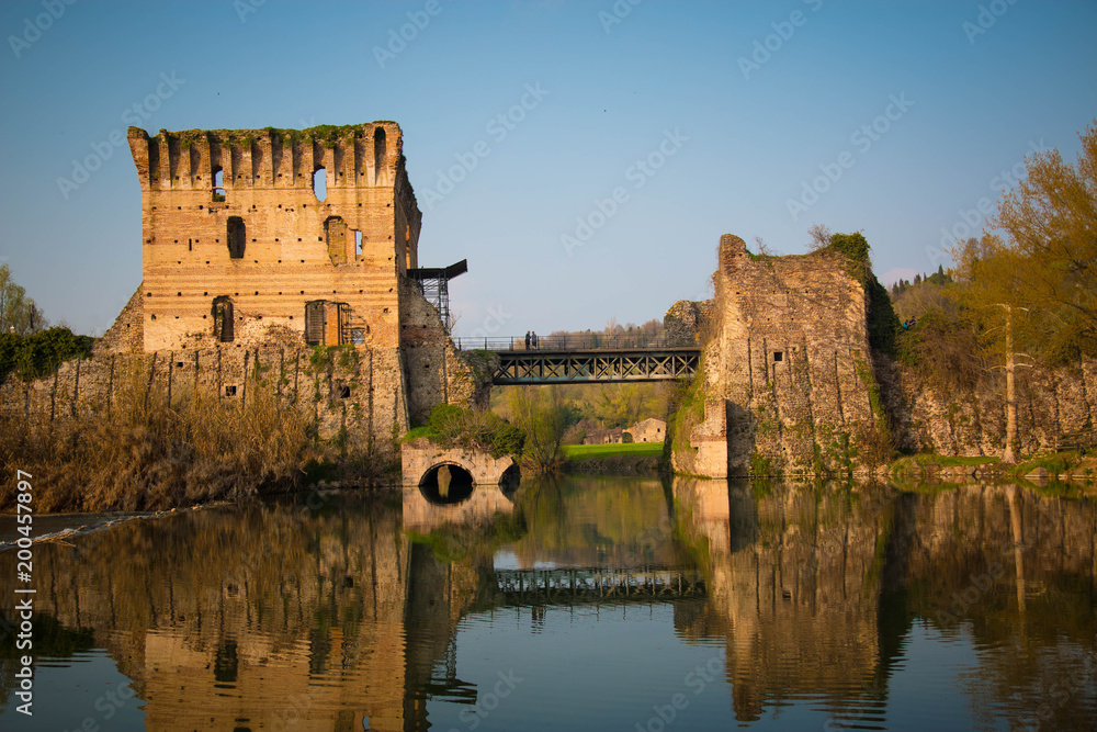 The ruins of Borghetto sul Mincio towers bridge on the river, with the pedestrial lane. Veneto region, Italy.