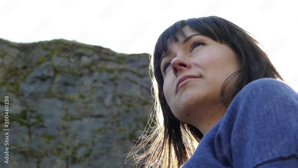 A beautiful girl looks into the distance. Beautiful woman looks at landscapes in a mountainous area. Long hair winds. Relaxing in nature A beautiful girl looks into the distance. Beautiful woman looks at landscapes in a mountainous area. Long hair winds. Relaxing in nature