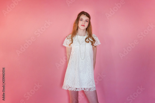 Happy teenage girl smiling. Closeup portrait young happy positive woman wearing white dress standing on pink colourful pastel trendy modern fashion pin-up background. European woman. Positive human em