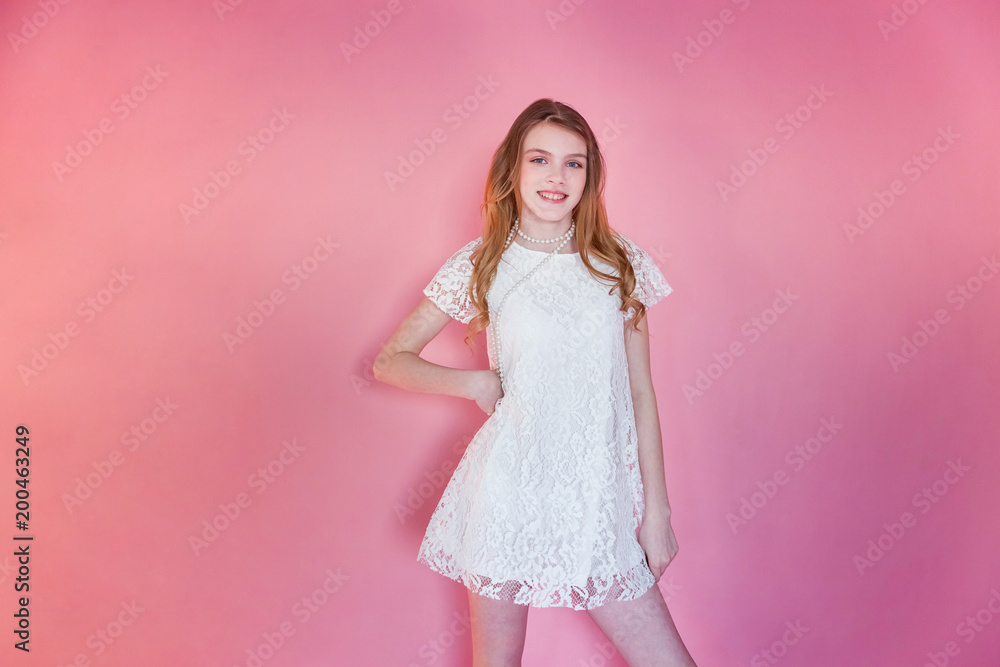 Happy teenage girl smiling. Closeup portrait young happy positive woman wearing white dress standing on pink colourful pastel trendy modern fashion pin-up background. European woman. Positive human em Happy teenage girl smiling. Closeup portrait young happy positive woman wearing white dress standing on pink colourful pastel trendy modern fashion pin-up background. European woman. Positive human em