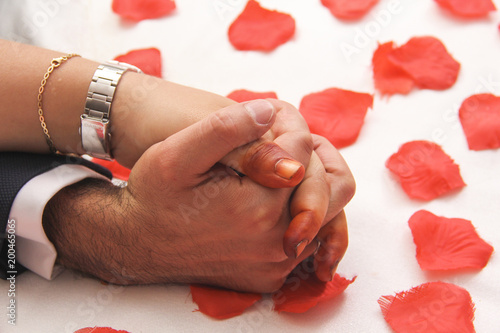 bride and groom holding hands with red rose leafs photo