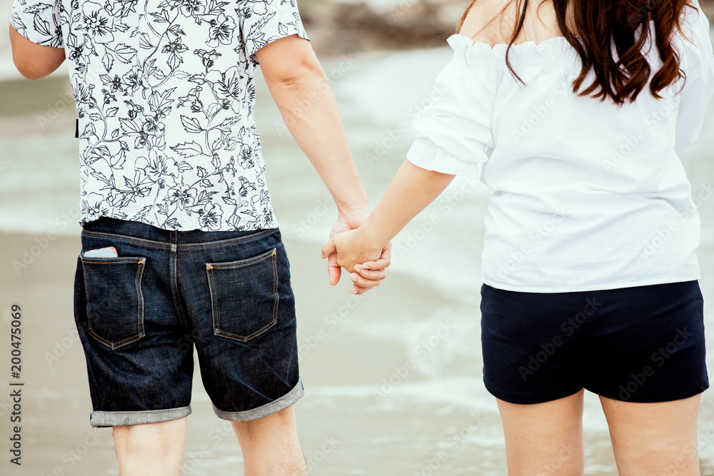 Lovers couple holding hands and walking on the beach together with love Lovers couple holding hands and walking on the beach together with love