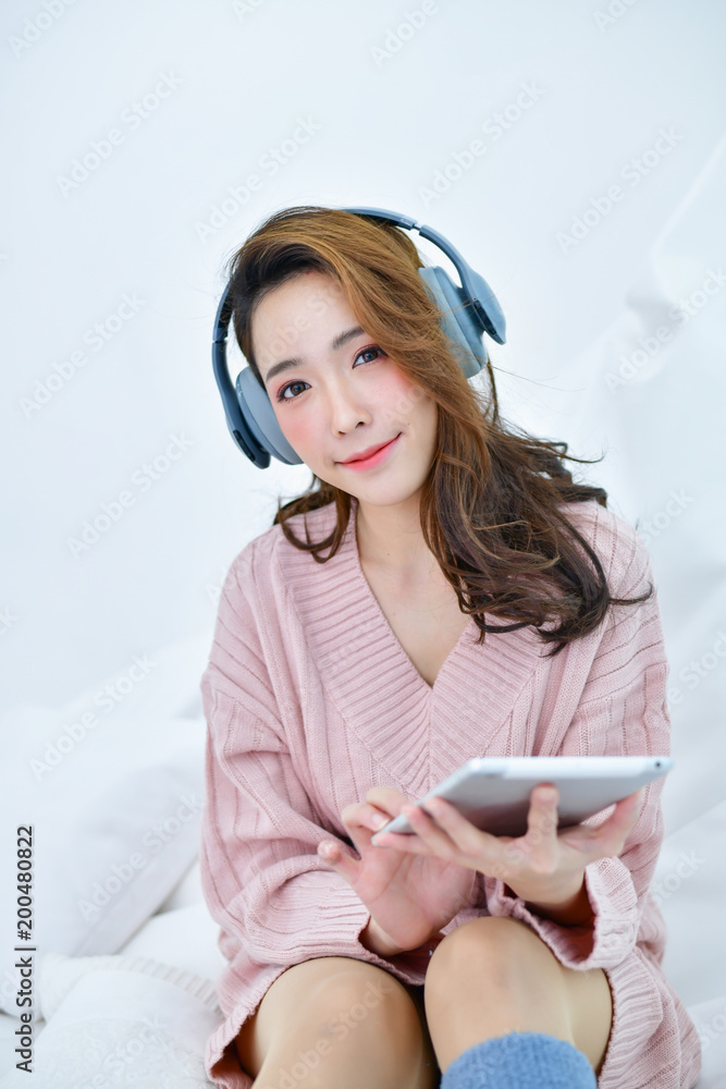 Winter Concept. Cute Asian girl in winter dress. Beautiful woman is relaxing  in a white bedroom. Stock Photo