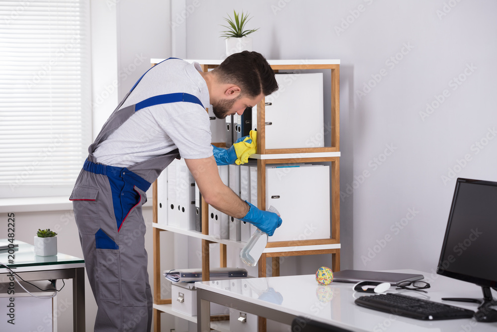 Man Cleaning Desk In Office