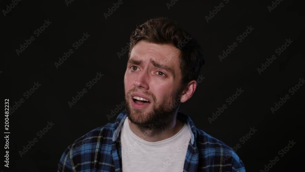 An attractive young man showing an I can't hear gesture against a black background. Close-up Shot An attractive young man showing an I can't hear gesture against a black background. Close-up Shot