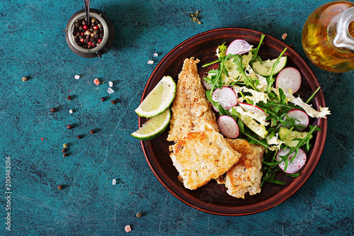 Canvas Print Fried white fish fillet and cucumber and radish salad. Top view