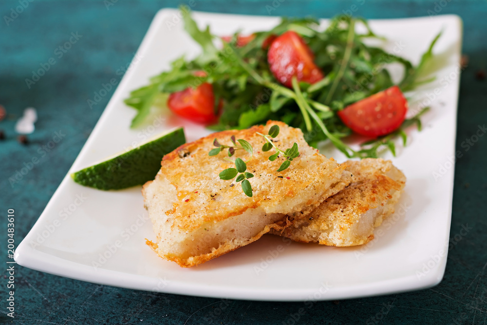 Fried white fish fillets and tomato salad with arugula.