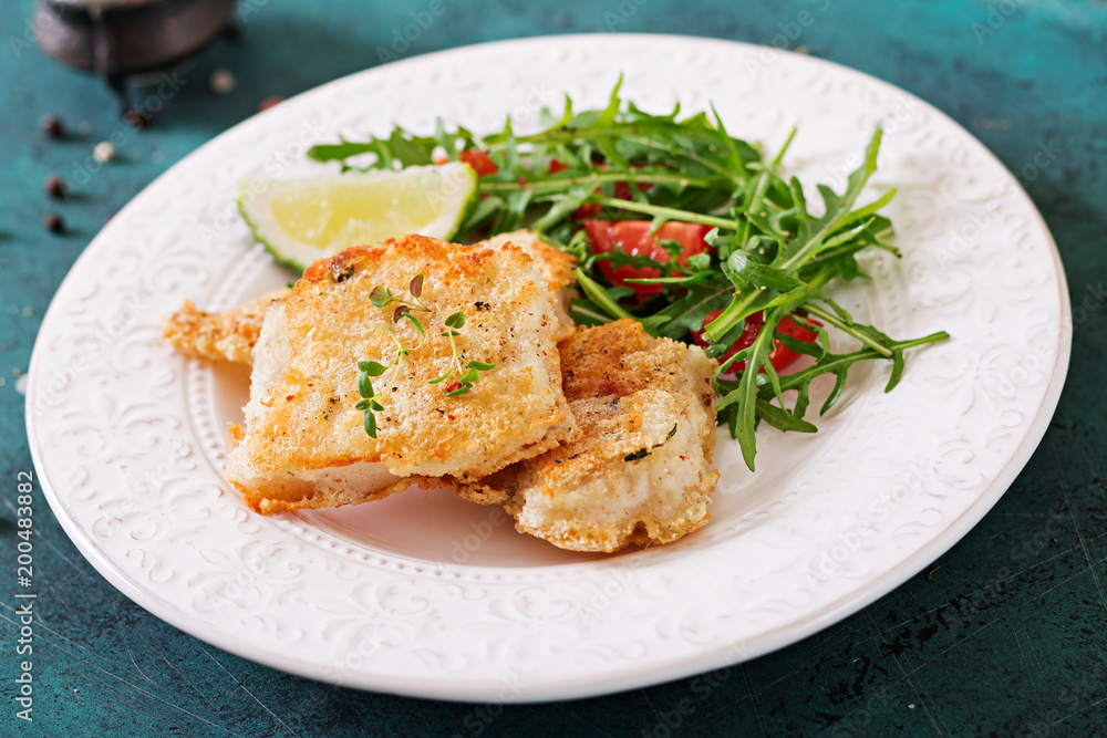 Fried white fish fillets and tomato salad with arugula. Fried white fish fillets and tomato salad with arugula.