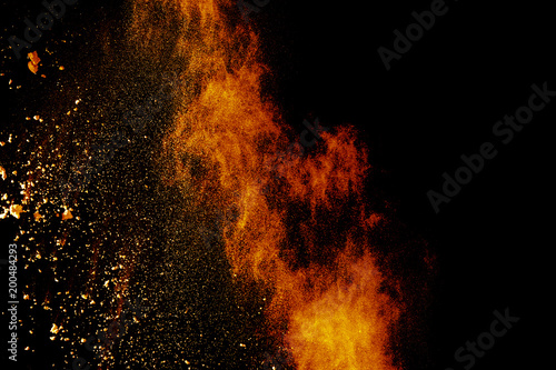 Red orange color powder explosion cloud isolated on black background.