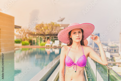 Swimsuit Concept. Beautiful girl wearing pink swimsuit. Beautiful girl in swimwear is relaxing at the swimming pool. Independent living sexy woman at the city center pool.