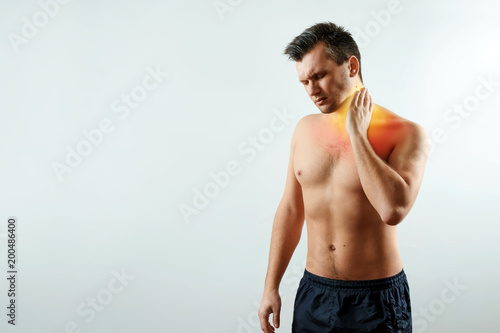 Front view, the man holds his hands behind the neck, the pain in the neck highlighted in red. Light background. The concept of medicine, massage, physiotherapy, health.