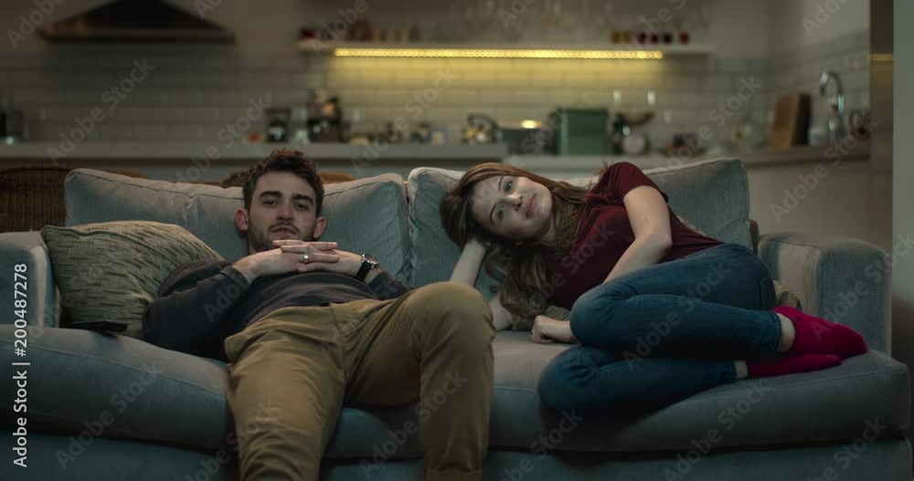 Young, good-looking couple relaxing on a sofa watching television. Young, good-looking couple relaxing on a sofa watching television.