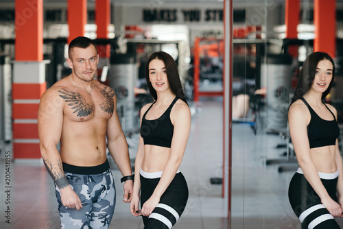 A man and a woman of a sports body build together in the gym