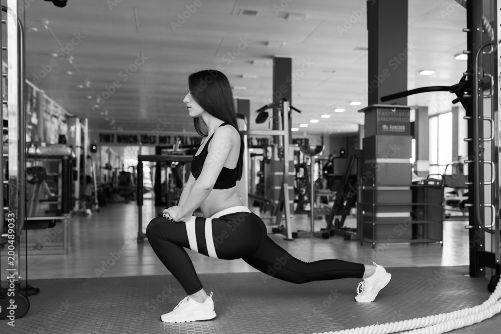 Beautiful sexy woman with a sports body in black and white sportswear trains in the gym Beautiful sexy woman with a sports body in black and white sportswear trains in the gym