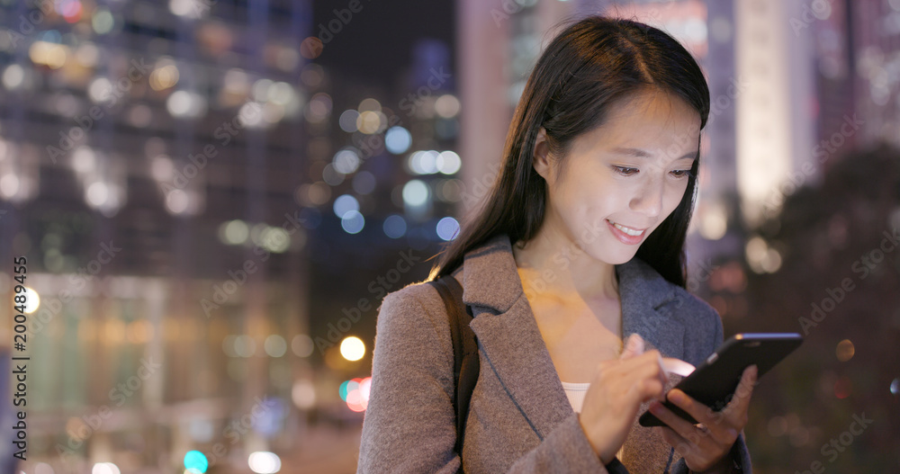 Asian Business woman watch on smart phone in city at night