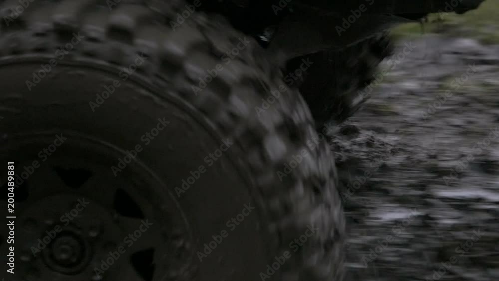 Close up, slow motion shot of off-road vehicles front entering very muddy terrain, splashing mud around and driving away. Close up, slow motion shot of off-road vehicles front entering very muddy terrain, splashing mud around and driving away.