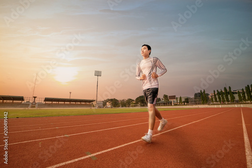 Athlete runs around the stadium with sunset or sunrise background