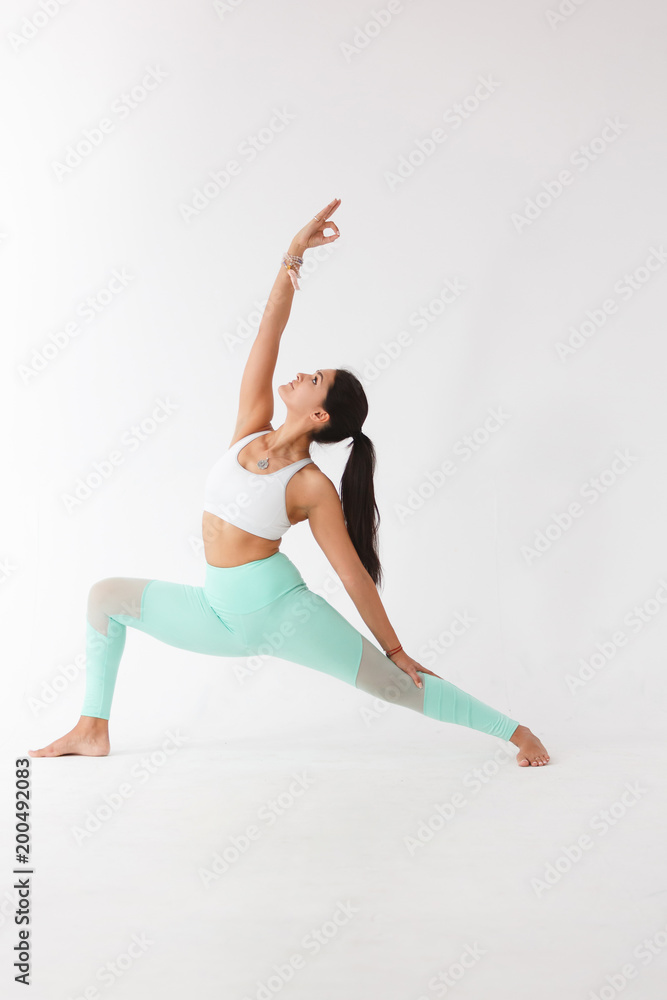 Beautiful graceful young woman in gymnastic costume doing pilates, yoga exercise or gymnastics for stretching hands and feet on white isolated background