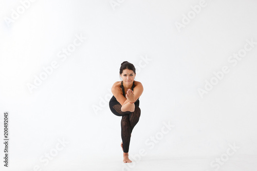 Beautiful sporty yogi girl wearing black sportwear practices yoga asana, Garudasana,Eagle Pose on white background, Healthy life yoga concept. Black and white concept.